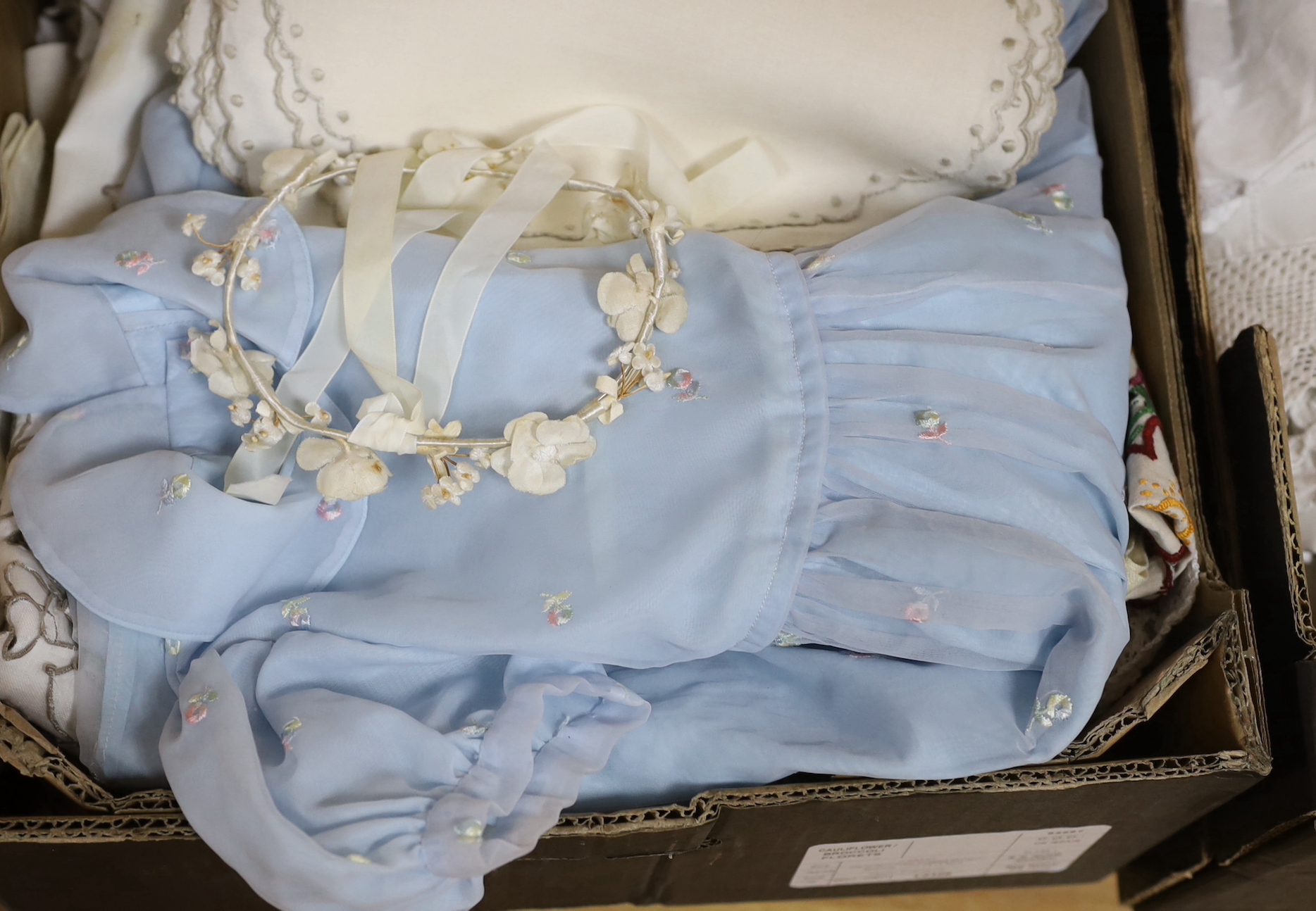 A 19th century white worked and hand made lace christening gown with a collection of table linens and a collection of coloured embroidered linens and a child's dress (2 boxes)